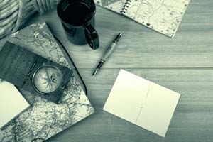Flat lay of notepad with a map and compass.