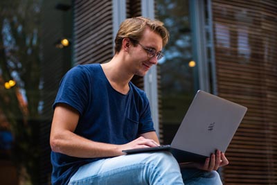 A photo of a man in a blue shirt, looking at something on his laptop