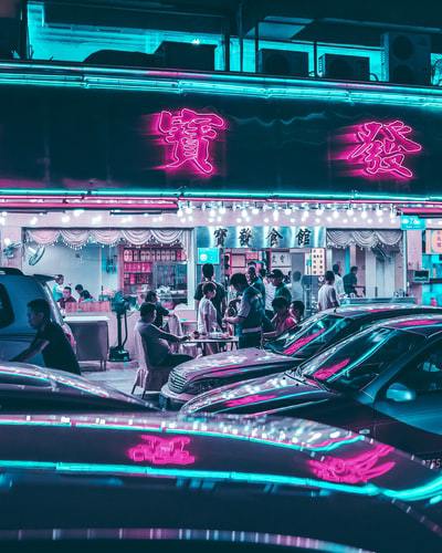A photo of a neon lit Chinese store sign along a busy street in Shenzhen, China