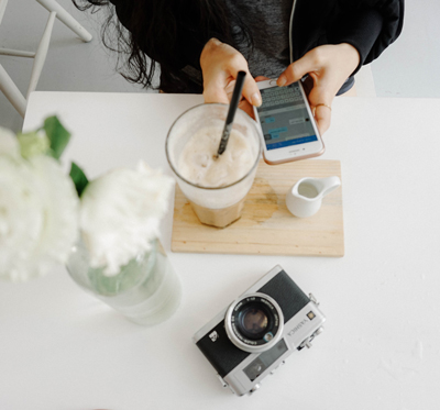 person sitting using iPhone on white table with camera on top