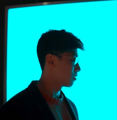 A man in glasses in front of a blue light