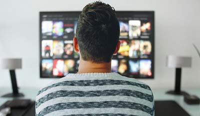 A man watching TV in his couch.