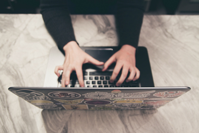 A person typing on a black laptop computer