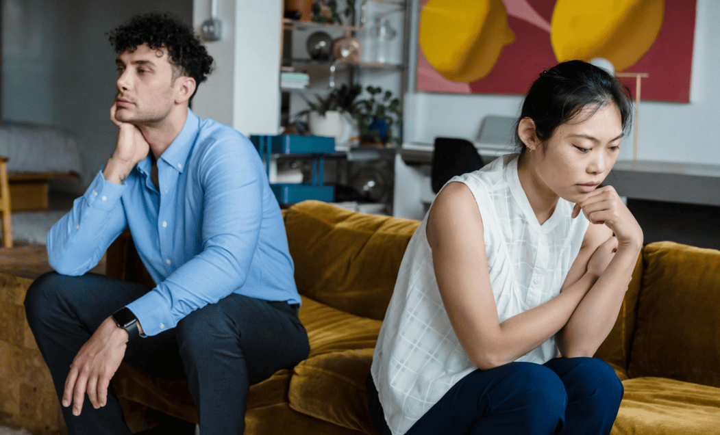 A couple sitting on a couch with their backs to each other