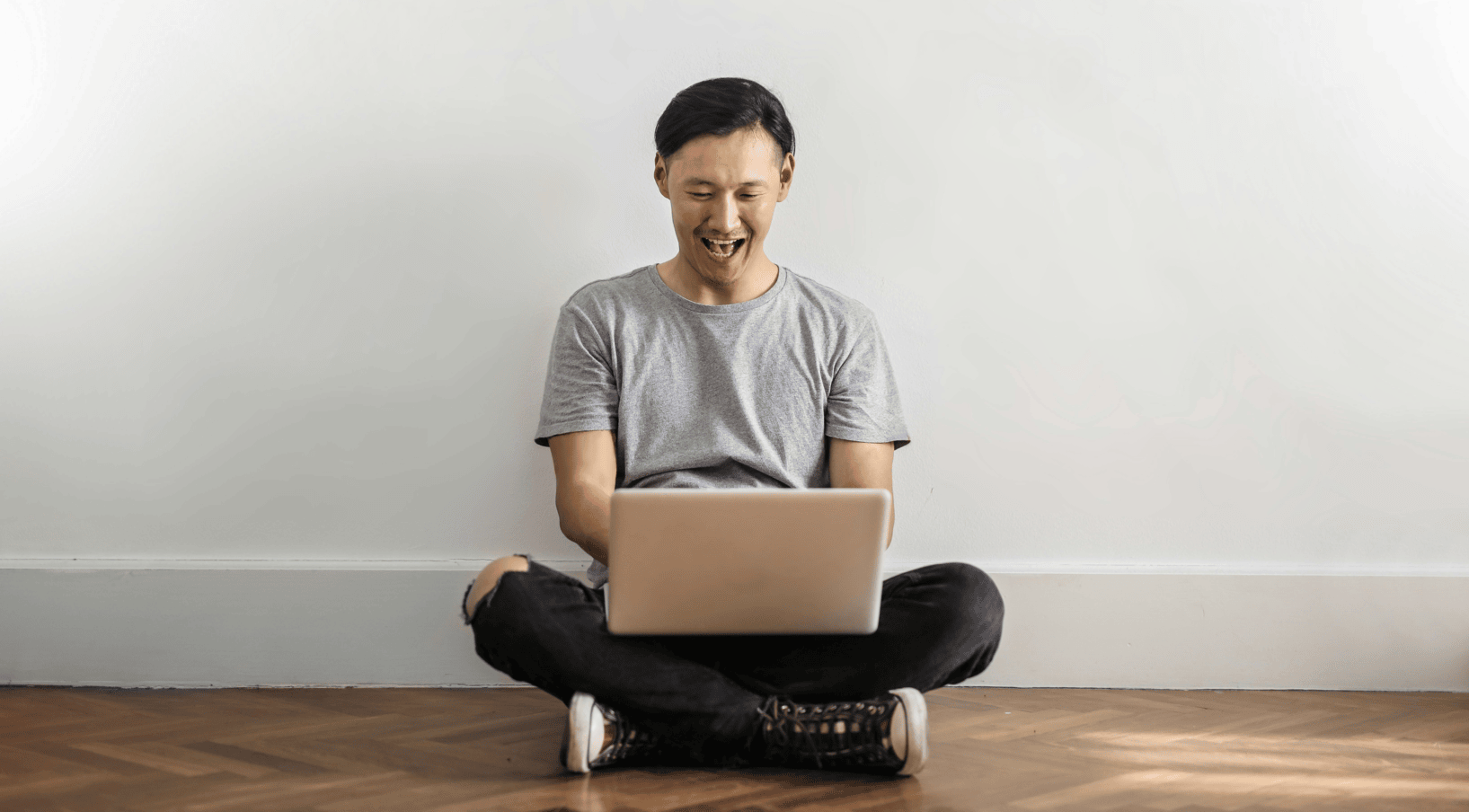 A man sitting on the floor while using his laptop
