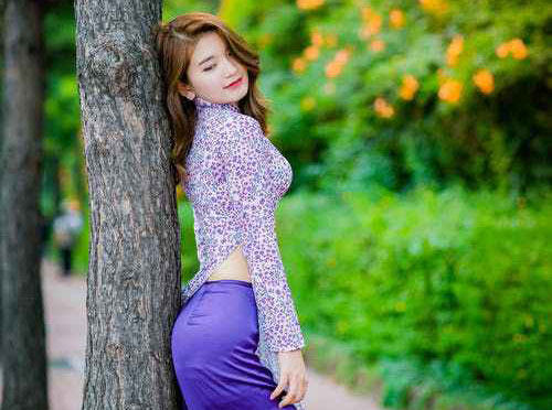 A young beautiful Chinese girl leaning on a tree