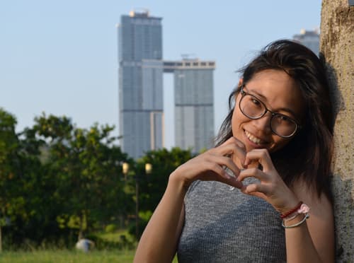 A photo of a Chinese woman doing a hand heart sign in Shenzhen China.