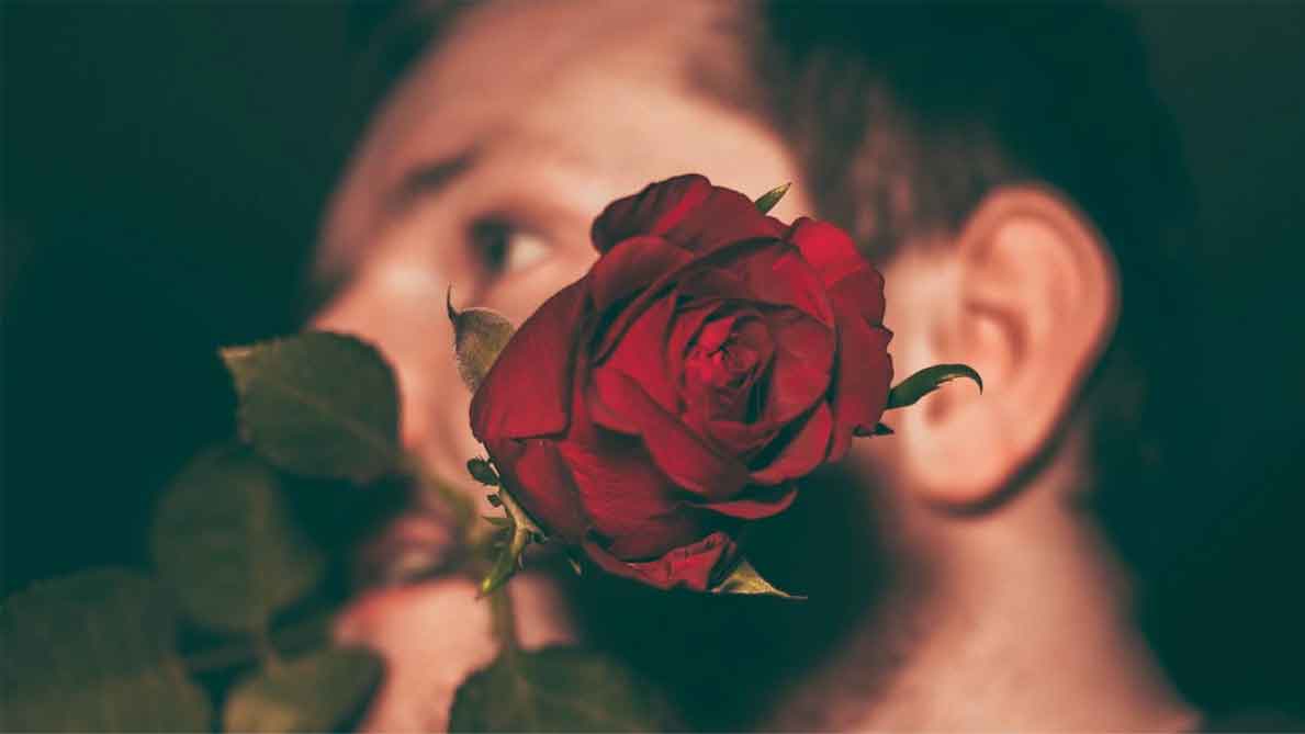 A photo of a man biting a red rose