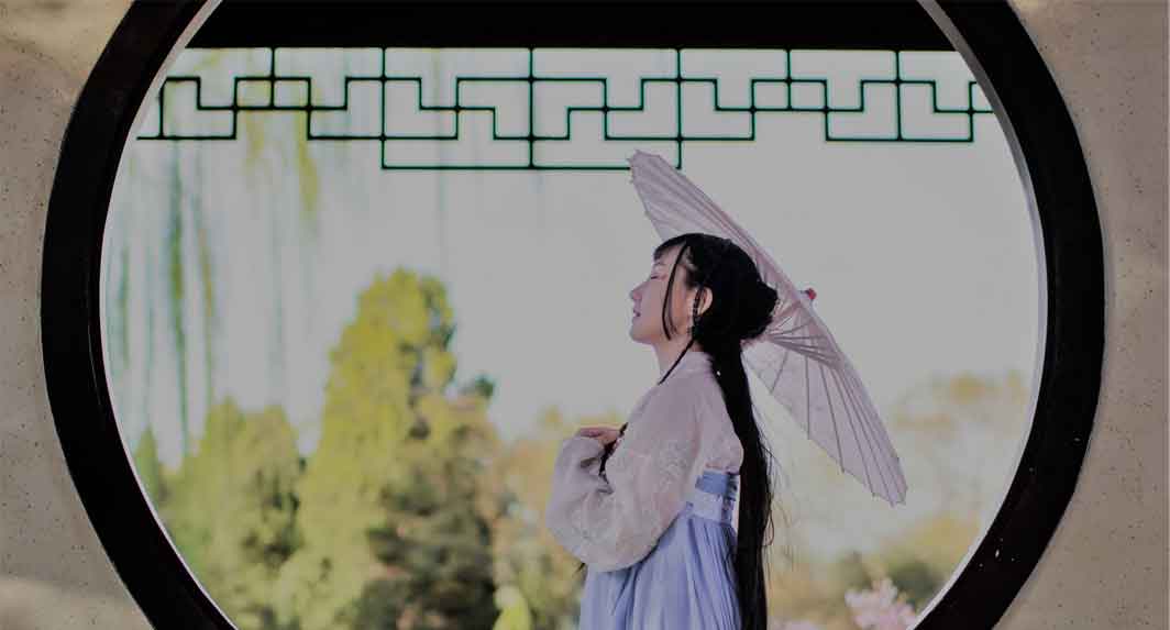 A photo of a Chinese girl in a white and blue dress holding an umbrella