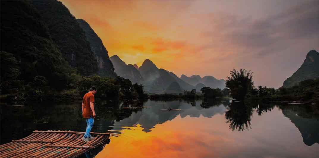 A photo of Yulong River in Guilin, China and a man on a bamboo raft