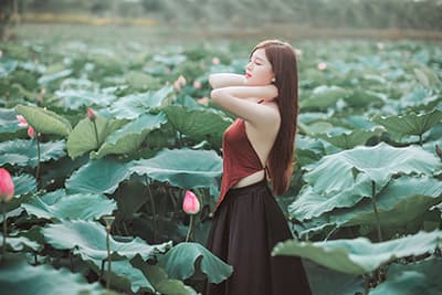 A beautiful Asian woman in a field of plants with big leaves